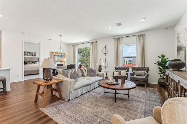 living room with dark hardwood / wood-style flooring, a notable chandelier, and a healthy amount of sunlight