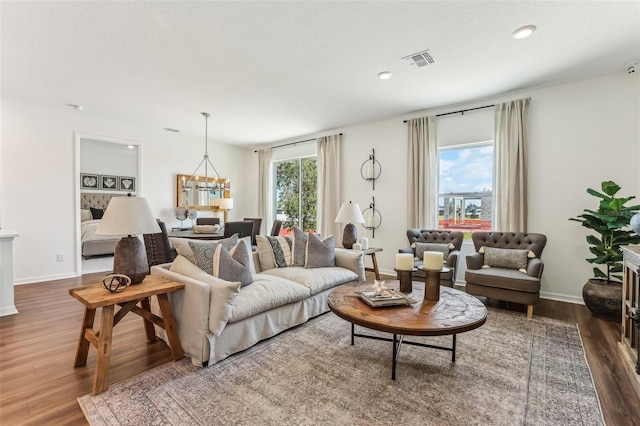 living room with dark wood-type flooring and an inviting chandelier