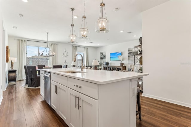 kitchen featuring a kitchen island with sink, sink, white cabinets, and decorative light fixtures