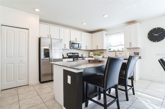 kitchen featuring white cabinetry, stainless steel appliances, a breakfast bar, and a kitchen island