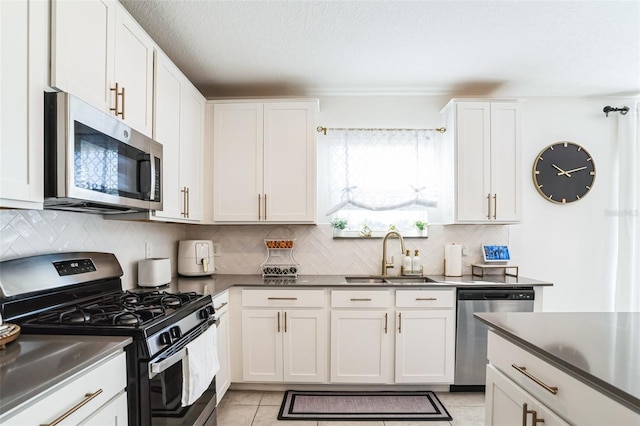 kitchen featuring appliances with stainless steel finishes, tasteful backsplash, white cabinetry, sink, and light tile patterned floors