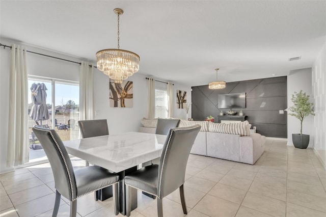 tiled dining room with a healthy amount of sunlight and a chandelier