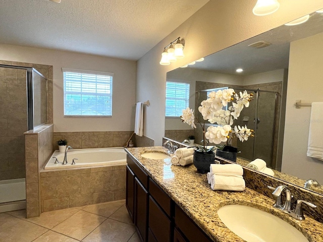 bathroom featuring plus walk in shower, a wealth of natural light, tile patterned floors, and a textured ceiling