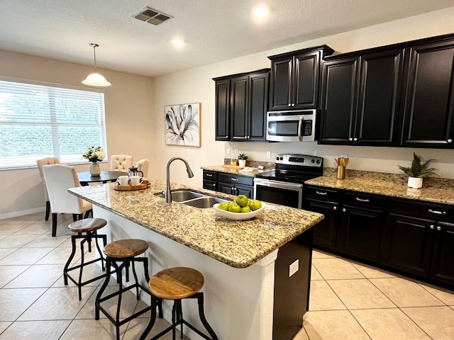 kitchen featuring an island with sink, appliances with stainless steel finishes, sink, and pendant lighting