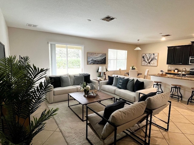 tiled living room featuring sink and a textured ceiling