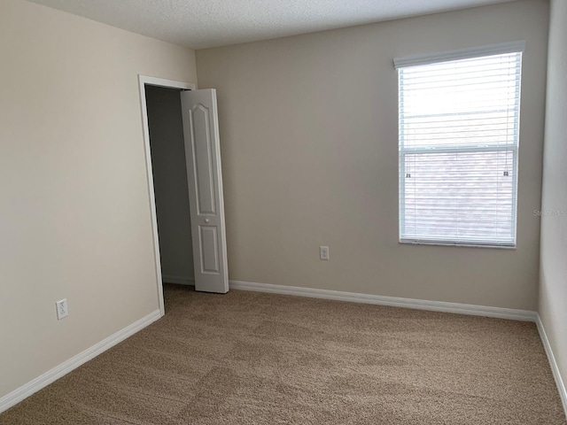 carpeted empty room featuring a textured ceiling