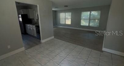 unfurnished room with light tile patterned flooring and baseboards