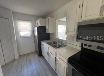 kitchen with white cabinetry, fridge, plenty of natural light, and sink