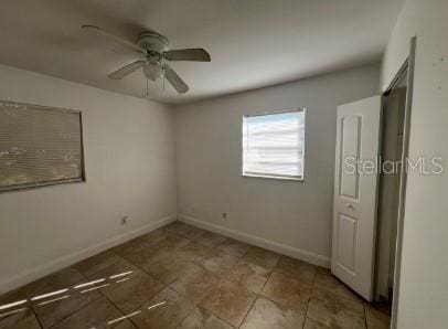 unfurnished room with dark tile patterned floors and ceiling fan