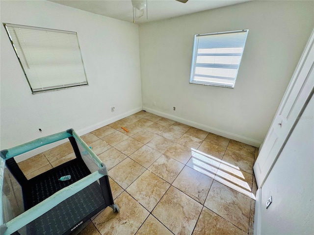 spare room with light tile patterned floors, baseboards, and ceiling fan