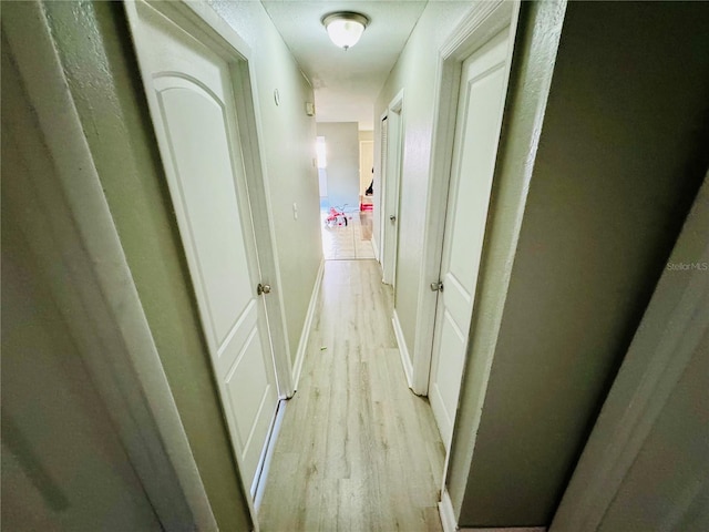 hall with baseboards and light wood-style floors