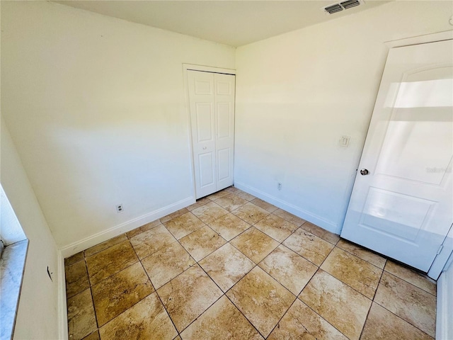 unfurnished bedroom featuring light tile patterned floors, baseboards, visible vents, and a closet