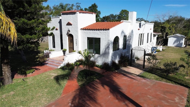 mediterranean / spanish house with a shed and a front lawn