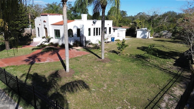 view of front of property with a patio area, a front lawn, and a shed