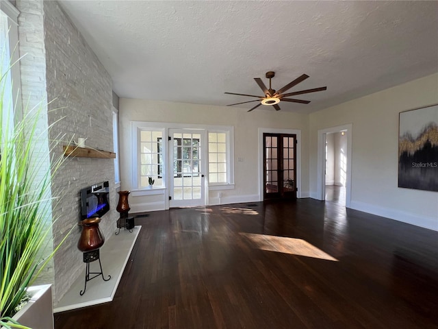 unfurnished living room with a large fireplace, dark hardwood / wood-style floors, french doors, and a textured ceiling