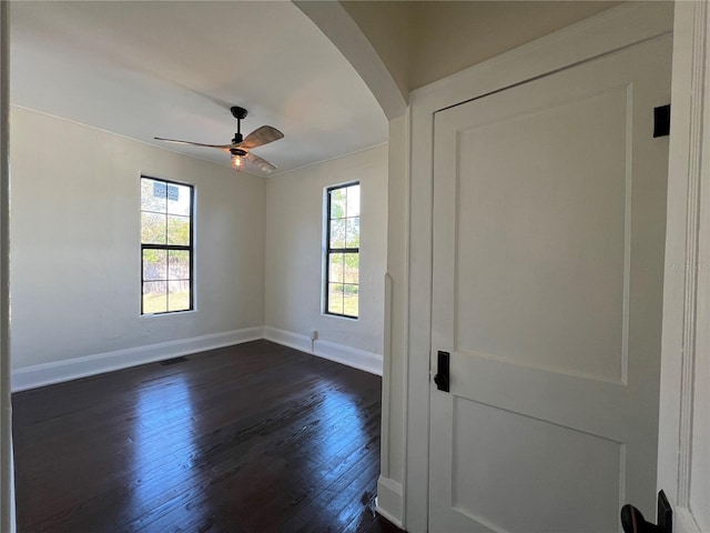 unfurnished room with dark hardwood / wood-style floors, a wealth of natural light, and ceiling fan