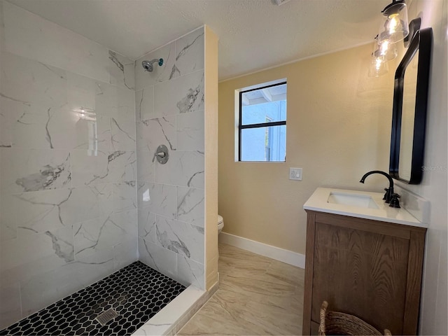 bathroom with vanity, toilet, and a tile shower