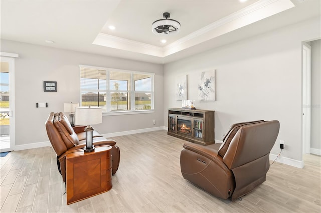 sitting room with a raised ceiling, crown molding, and light hardwood / wood-style floors