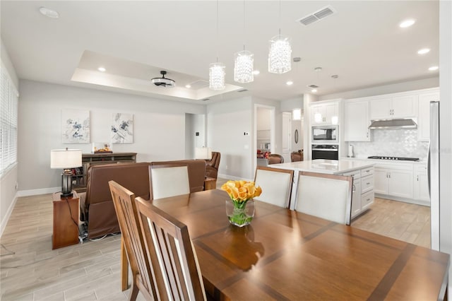 dining space with light hardwood / wood-style floors and a raised ceiling