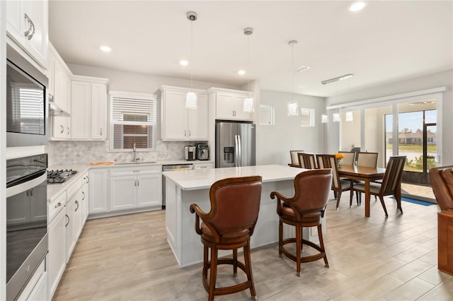 kitchen with hanging light fixtures, appliances with stainless steel finishes, a center island, and sink