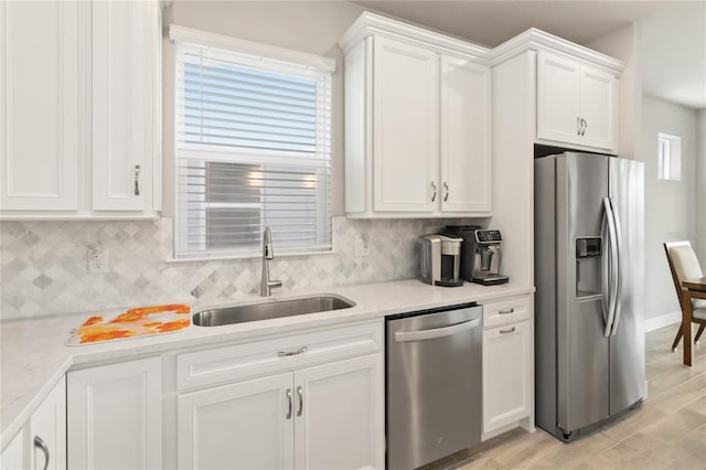 kitchen featuring sink, stainless steel appliances, light hardwood / wood-style floors, decorative backsplash, and white cabinets