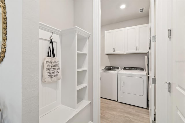 laundry area with cabinets, washing machine and clothes dryer, and light hardwood / wood-style flooring