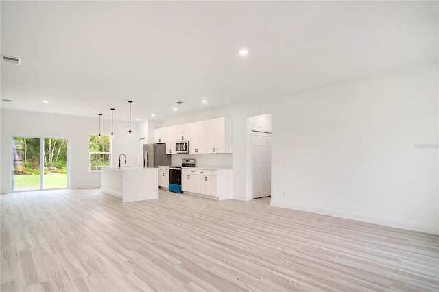 unfurnished living room with recessed lighting, visible vents, light wood-style floors, a sink, and baseboards