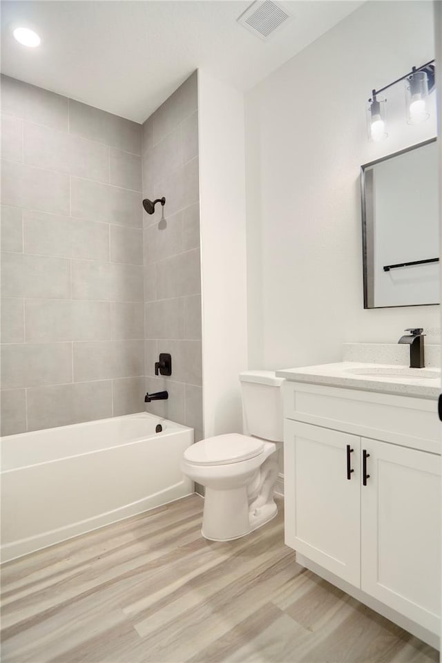 full bathroom with shower / bathtub combination, visible vents, toilet, vanity, and wood finished floors