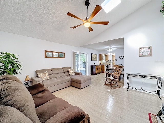 living room featuring ceiling fan, high vaulted ceiling, light hardwood / wood-style flooring, and a textured ceiling