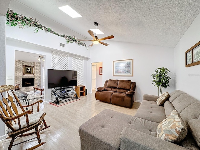 living room featuring lofted ceiling, a textured ceiling, ceiling fan, and light hardwood / wood-style flooring