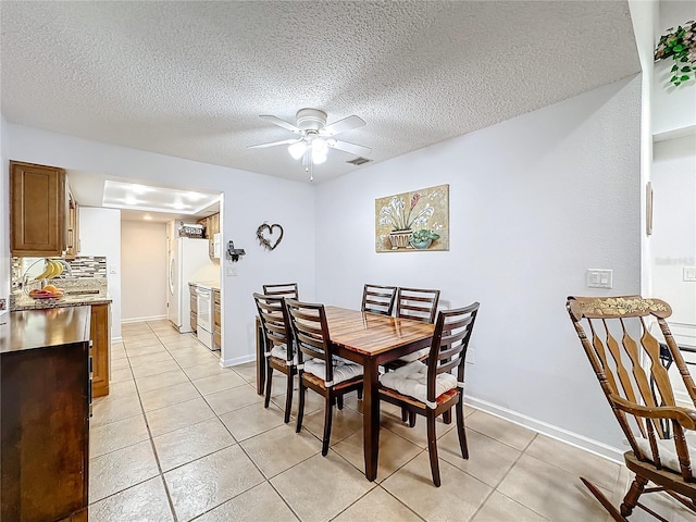 tiled dining space with ceiling fan and a textured ceiling