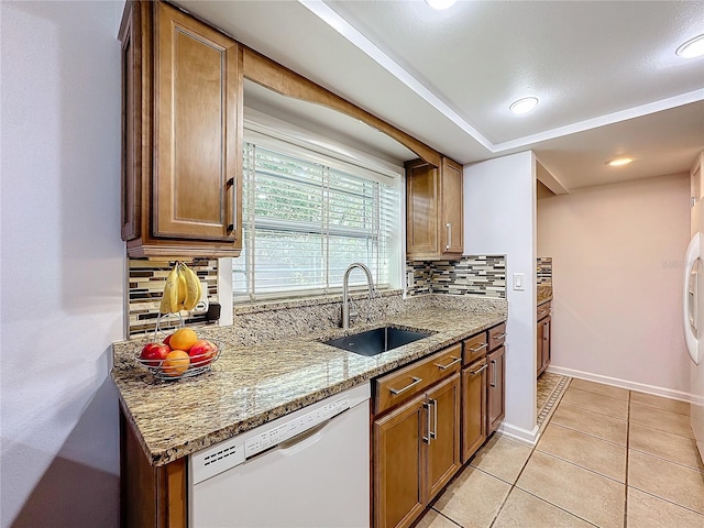 kitchen with sink, light tile patterned floors, dishwasher, backsplash, and light stone counters