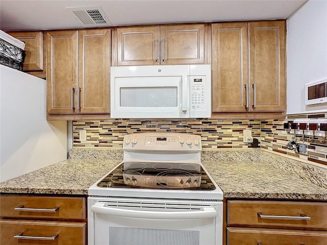 kitchen with light stone counters, white appliances, and decorative backsplash