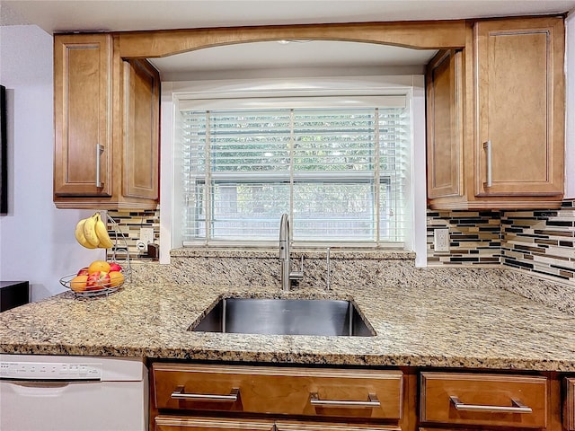 kitchen featuring dishwasher, sink, backsplash, and light stone counters