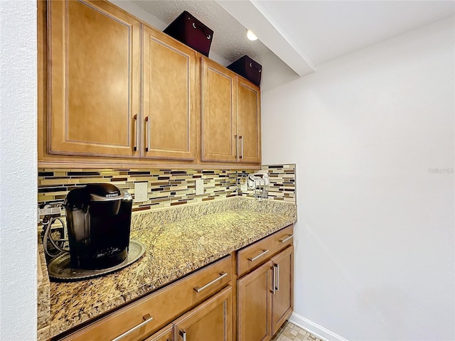 kitchen featuring light stone countertops and backsplash