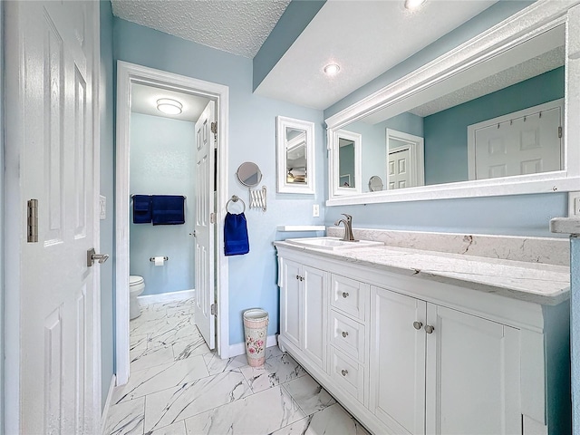 bathroom featuring vanity, toilet, and a textured ceiling