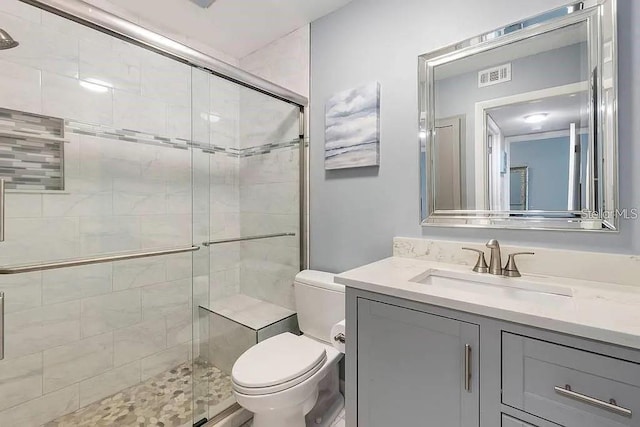 bathroom featuring vanity, a shower with shower door, and toilet