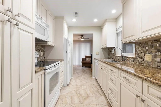 kitchen featuring white cabinetry, sink, decorative backsplash, dark stone counters, and white appliances