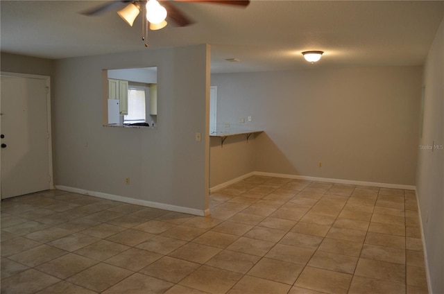 spare room with ceiling fan and light tile patterned floors