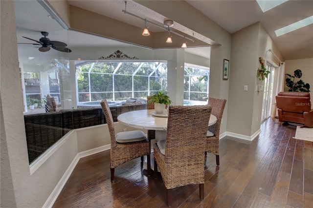 dining space with vaulted ceiling with skylight, baseboards, wood-type flooring, and a sunroom