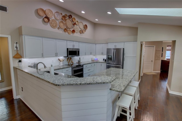 kitchen with visible vents, a sink, stainless steel appliances, a peninsula, and light stone countertops