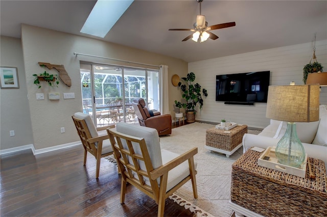 living area featuring baseboards, ceiling fan, wood finished floors, vaulted ceiling, and a sunroom