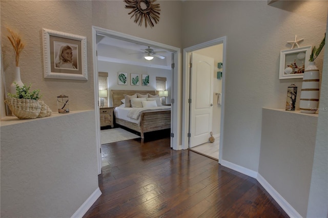 bedroom featuring a textured wall, baseboards, ceiling fan, and hardwood / wood-style flooring