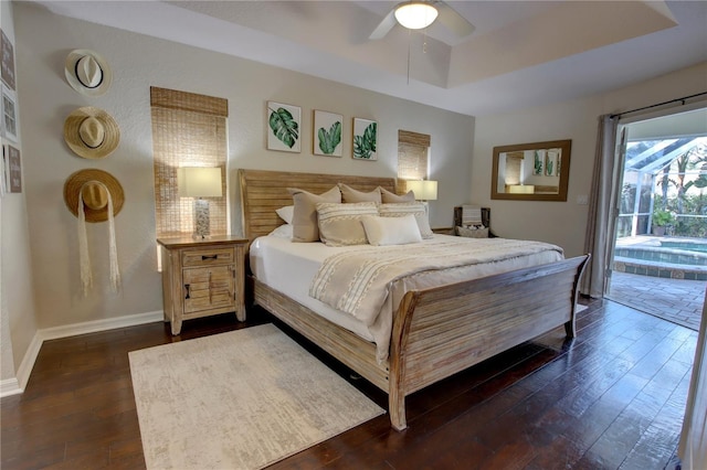 bedroom with dark wood-type flooring, baseboards, a tray ceiling, a ceiling fan, and access to outside