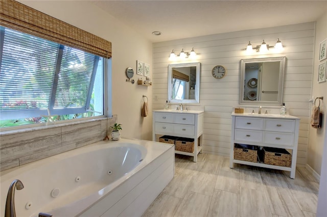 bathroom featuring a sink, two vanities, and a whirlpool tub