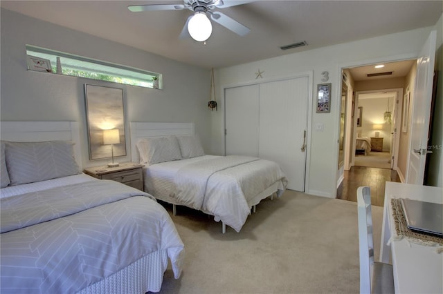 carpeted bedroom featuring visible vents, a closet, and a ceiling fan