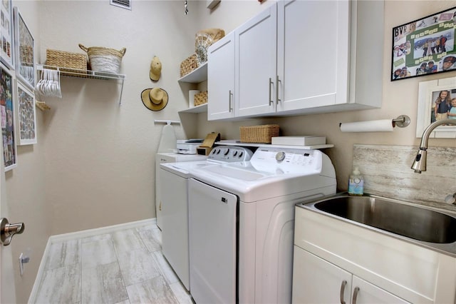 washroom featuring washer and dryer, baseboards, cabinet space, and a sink