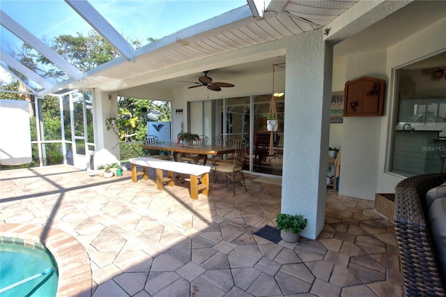 view of patio / terrace with outdoor dining space, glass enclosure, and ceiling fan