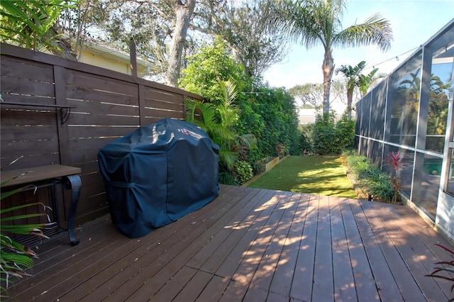 wooden terrace featuring grilling area, a lawn, and fence