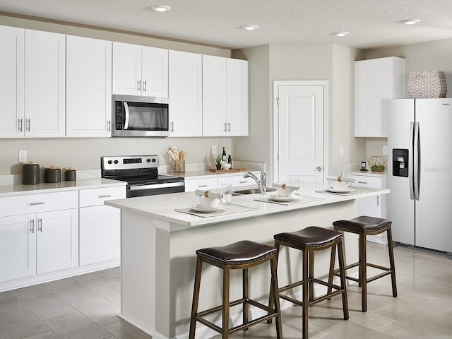 kitchen featuring stainless steel appliances, white cabinetry, sink, and a center island with sink